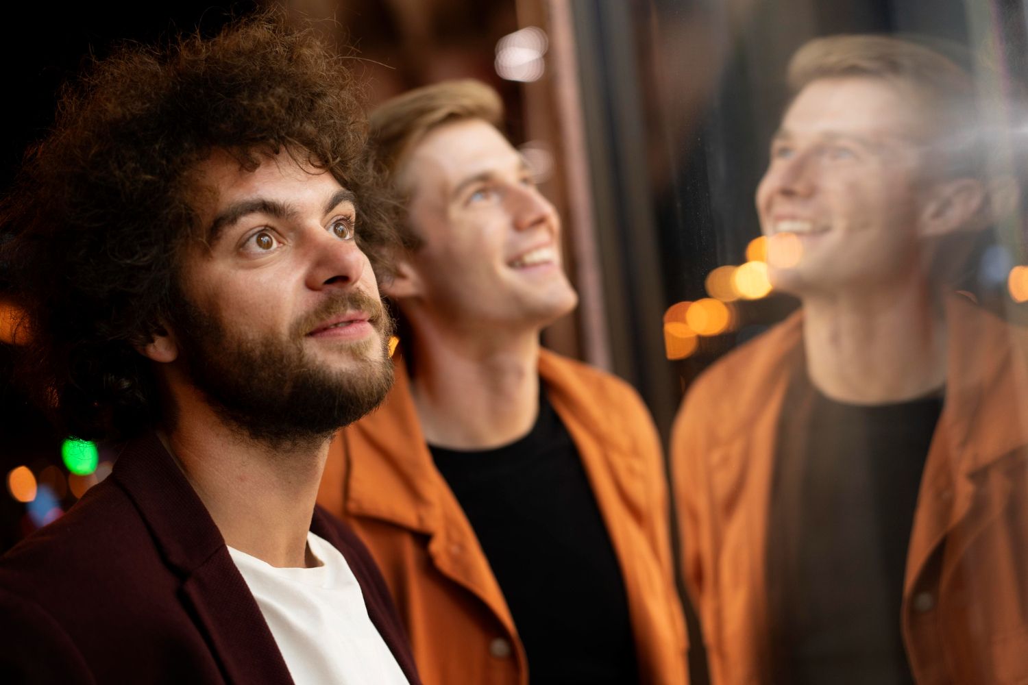 Dois homens olhando com surpresa para uma vitrine iluminada à noite
